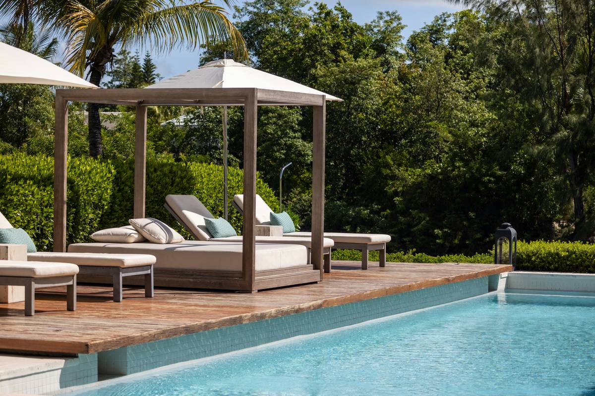 Pretty outdoor furniture for poolside featuring teak loungers and weather-resistant cushions around a blue-tiled pool